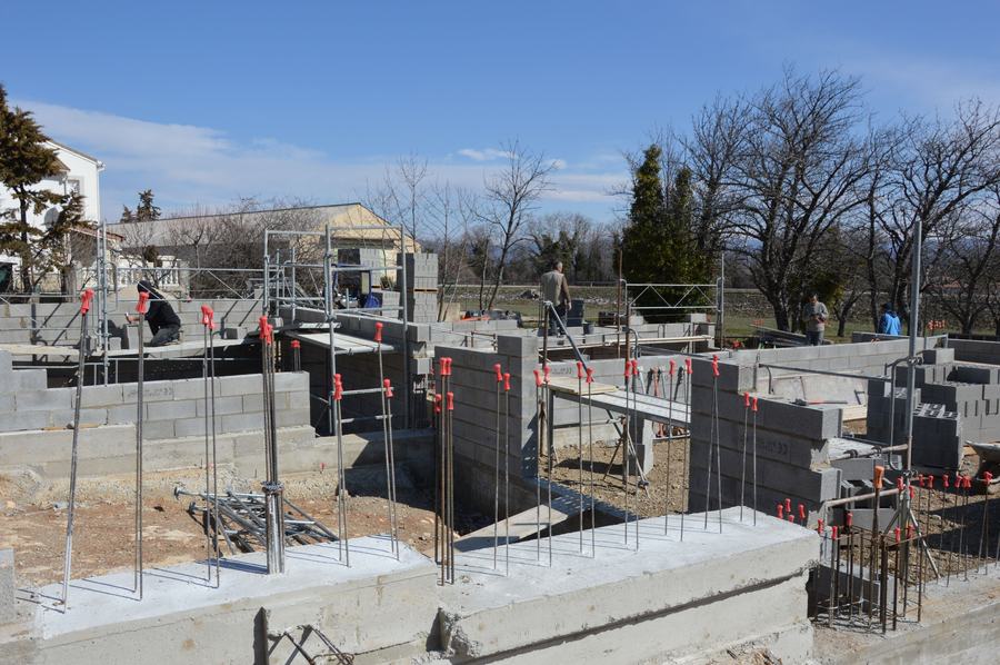 Chantier de fondations en béton et parpaings avec des ouvriers sur les murs